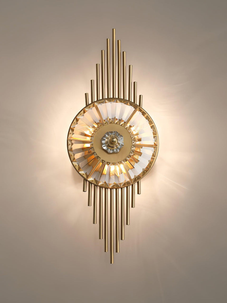 The sconce lit warm on a beige wall, light radiating from the crystal wheel