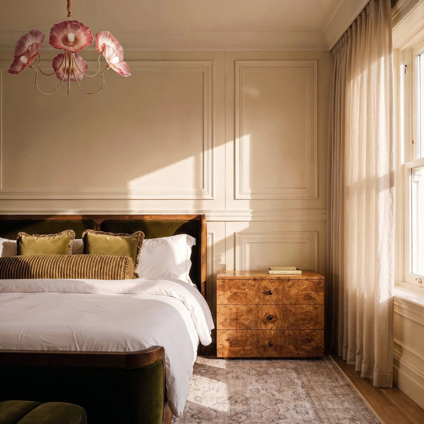 The red version lit above a bed with a burl wood dresser and a window