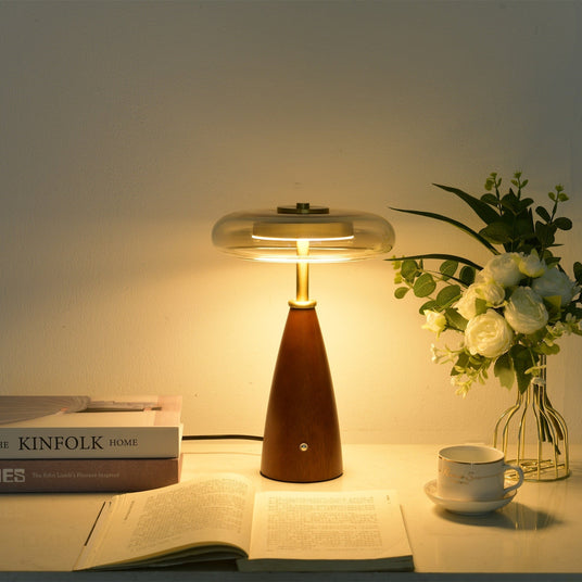 Clear glass table lamp lit close, the gold cap seen through the glass