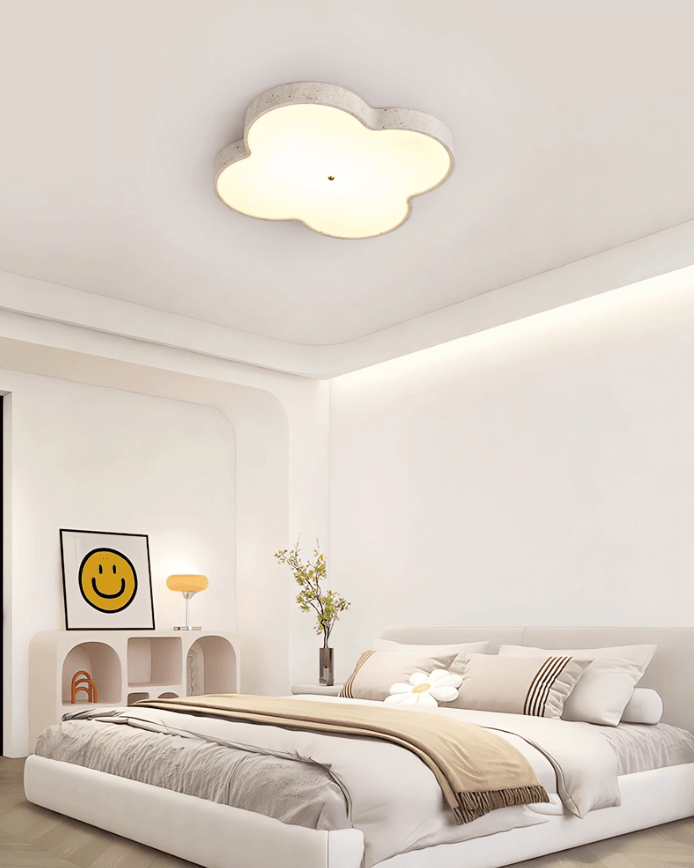 Cloud ceiling lamp lit in a bedroom with a framed print and a rounded headboard