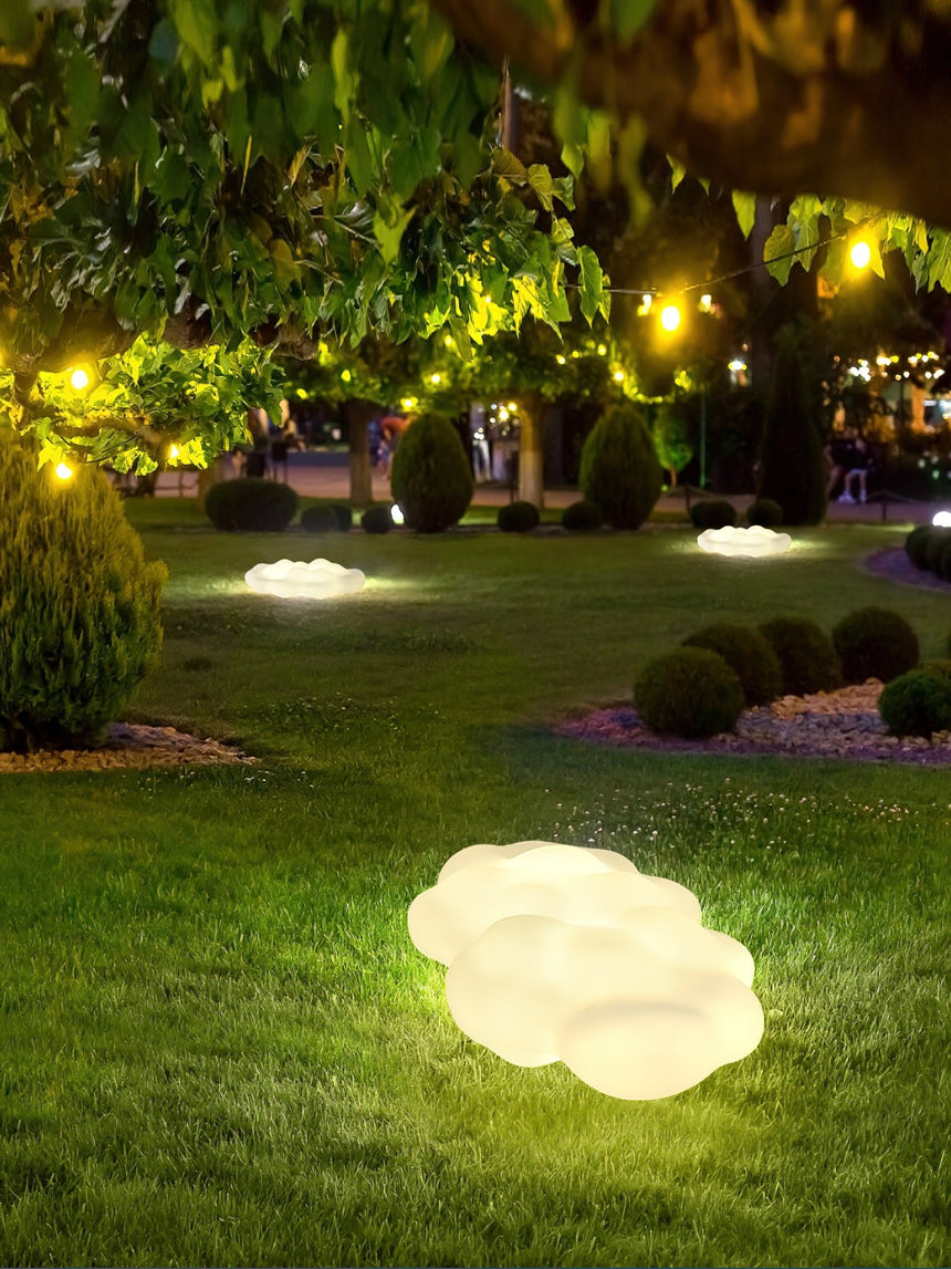 The cloud lit on a lawn under trees with a lit house behind it