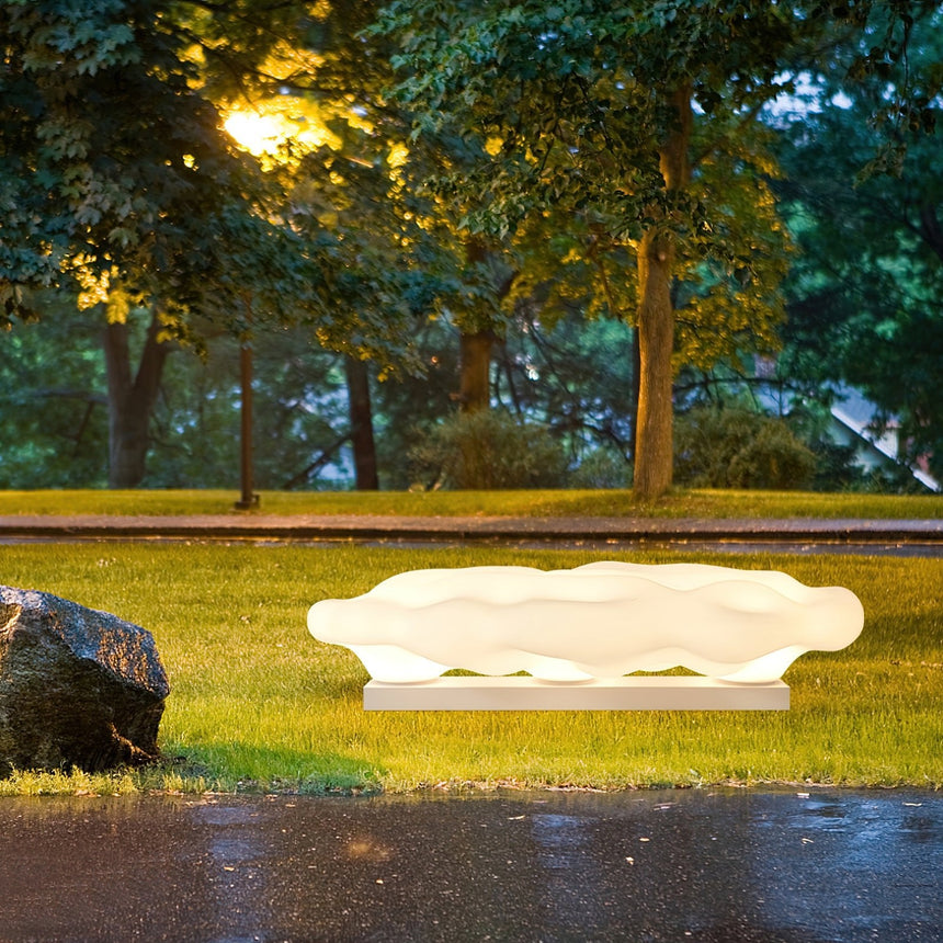 The cloud lit on wet grass beside paving reflecting the light
