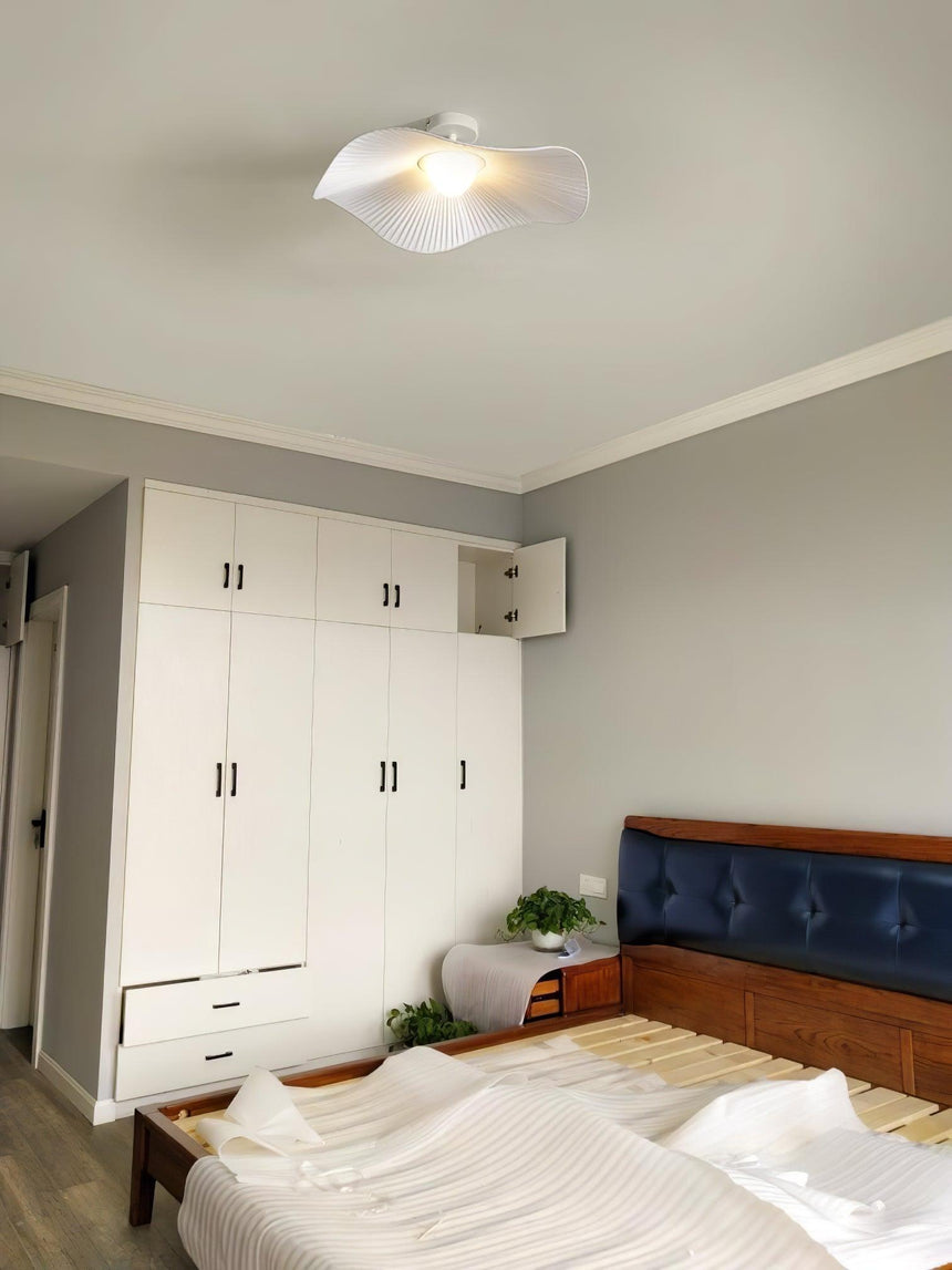 Fabric wing ceiling light in a bedroom with white wardrobes and a dark wood headboard