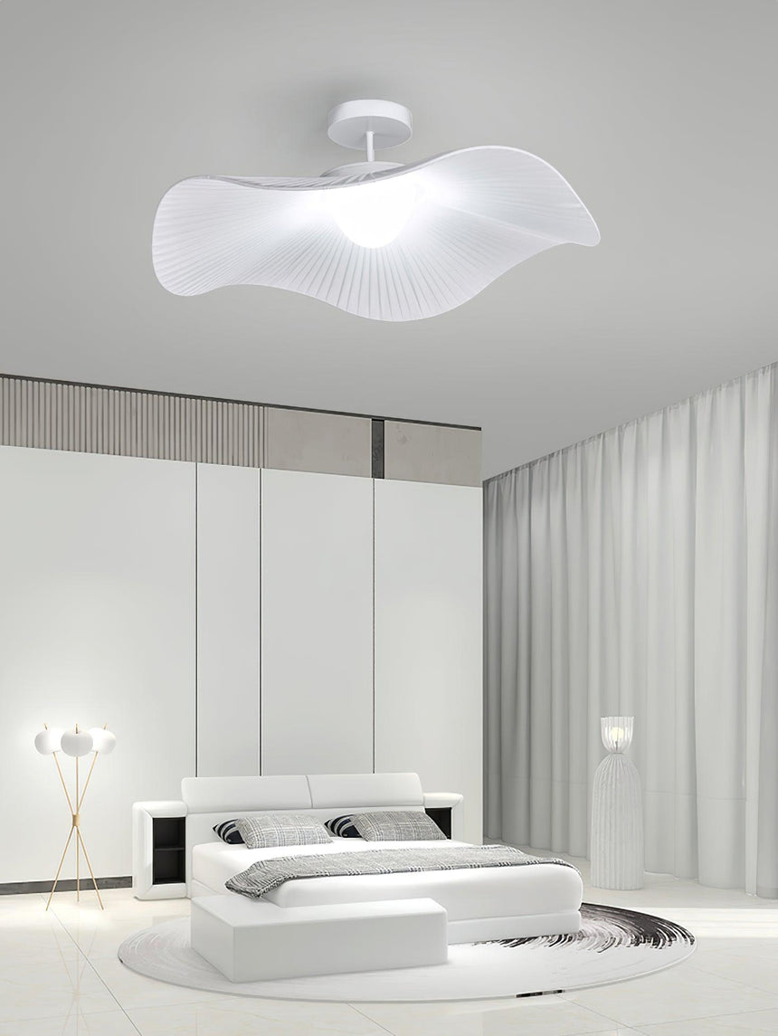 Fabric wing ceiling light in a white bedroom with a low platform bed and a floor lamp