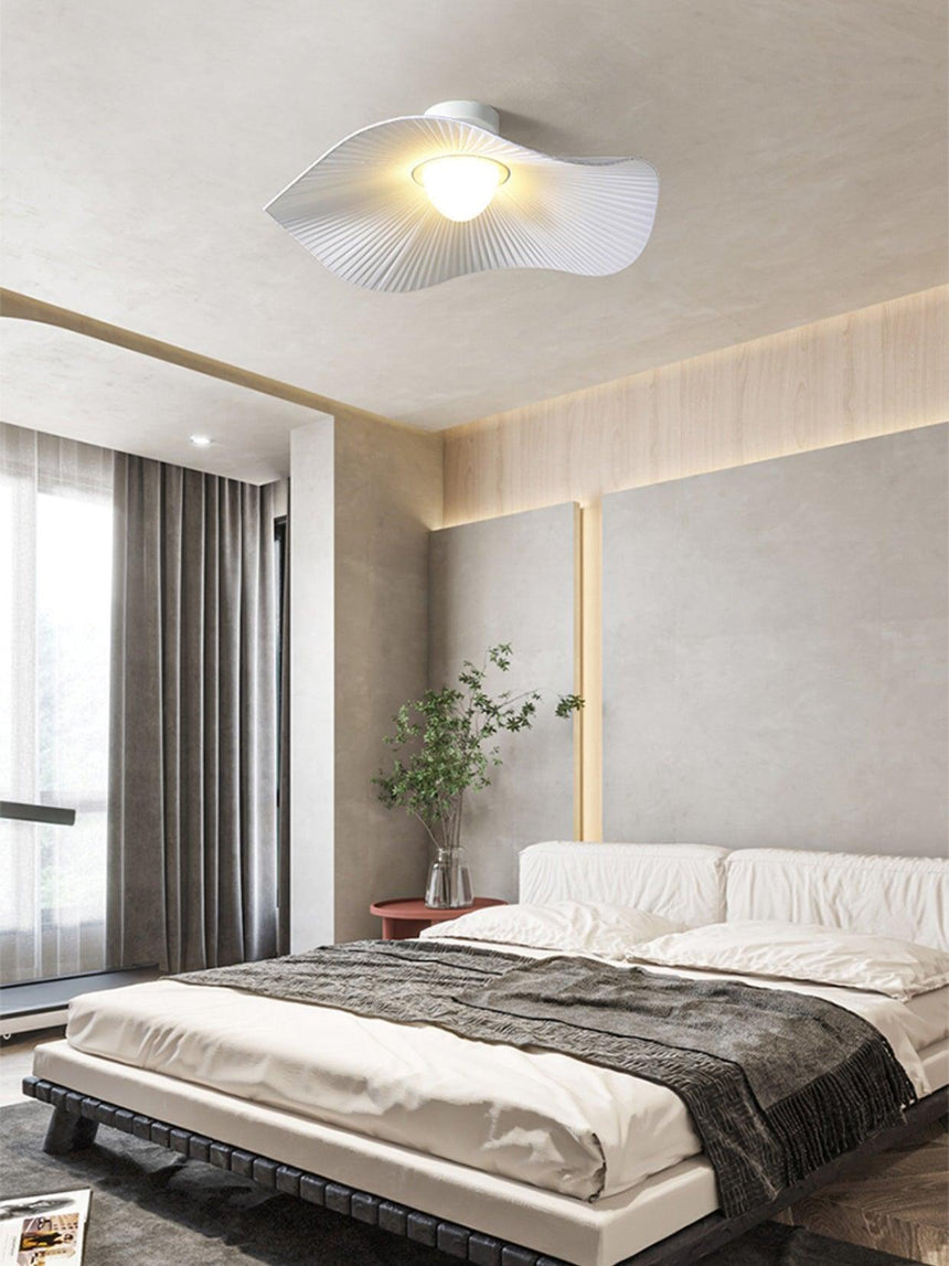 Fabric wing ceiling light above a bed with dark bedding and a wood slat wall