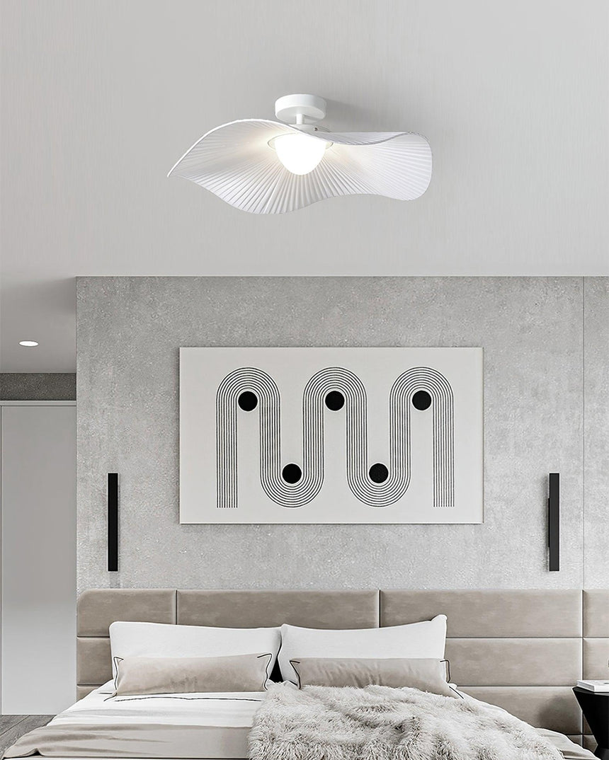 White fabric ceiling fixture over a bed with an upholstered headboard and a framed panel