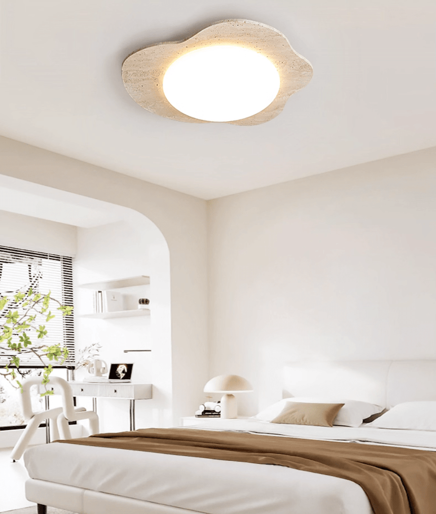 Travertine cloud ceiling light lit in a bedroom beside a window with greenery outside