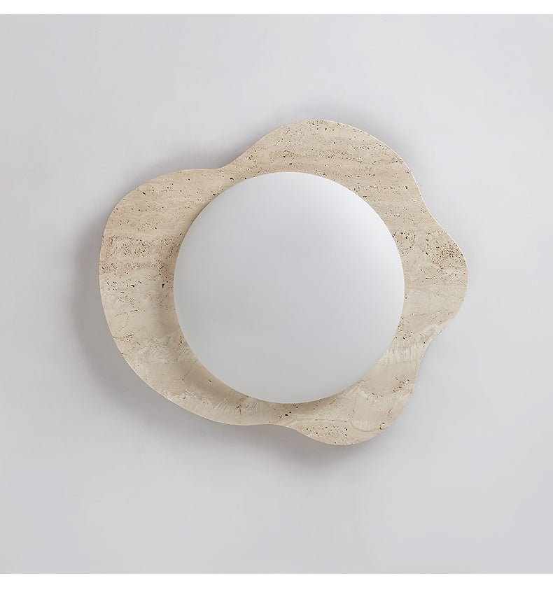 Close view of the unlit travertine frame and the round white lens at its center