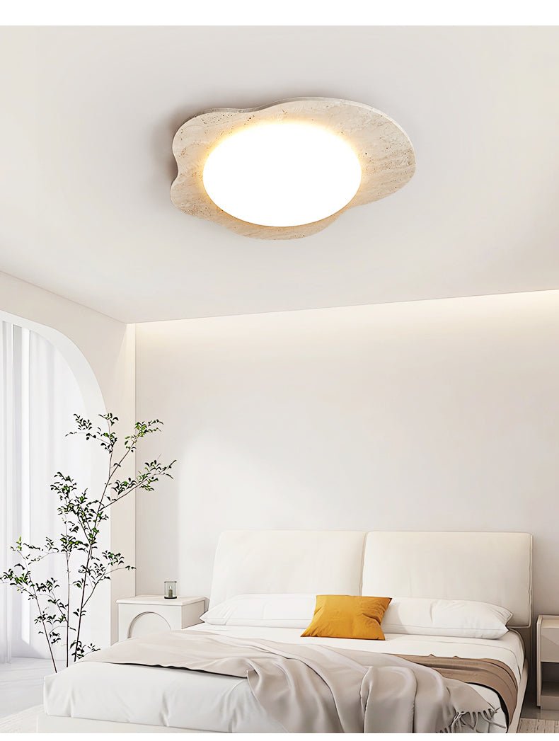 Travertine cloud ceiling light lit in a bright bedroom with a bamboo plant