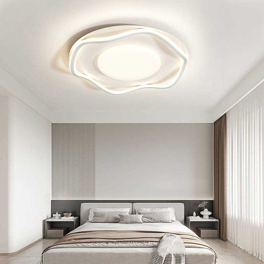 Cloud outline ceiling lamp lit over a bed with bedside tables and a tall headboard