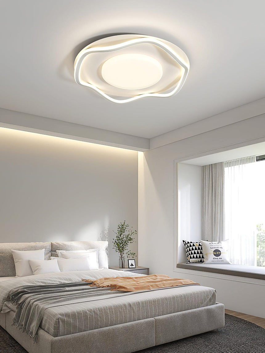 Cloud shaped ceiling lamp lit in a bedroom with a window seat and gray bedding