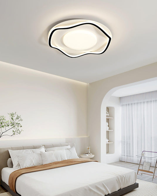 Cloud shaped ceiling lamp in black and white above a bed near an arched doorway
