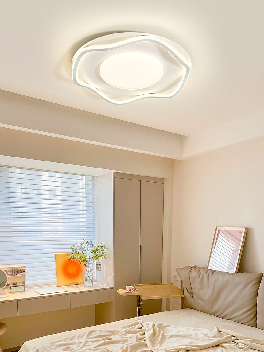 Cloud shaped ceiling lamp lit in a bedroom with a blind, a desk and a framed print