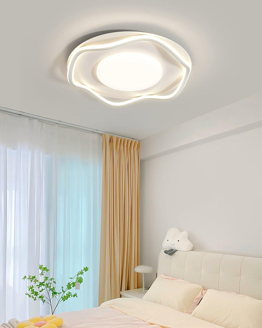 Cloud shaped ceiling lamp above a sofa bed with a plant and sheer curtains