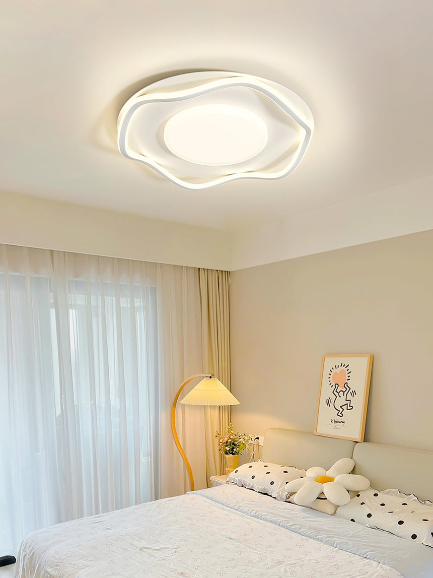 Cloud shaped ceiling lamp in a bedroom with a table lamp and yellow curtains