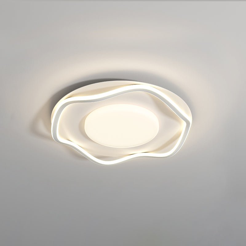 White cloud shaped ceiling lamp lit at an angle against a plain pale wall