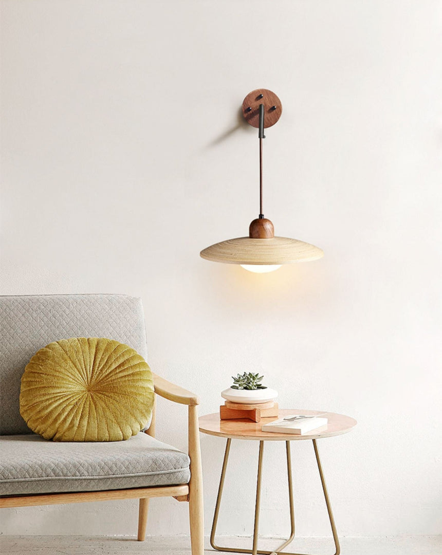 Sconce lit above a side table of plants beside an armchair with a cushion