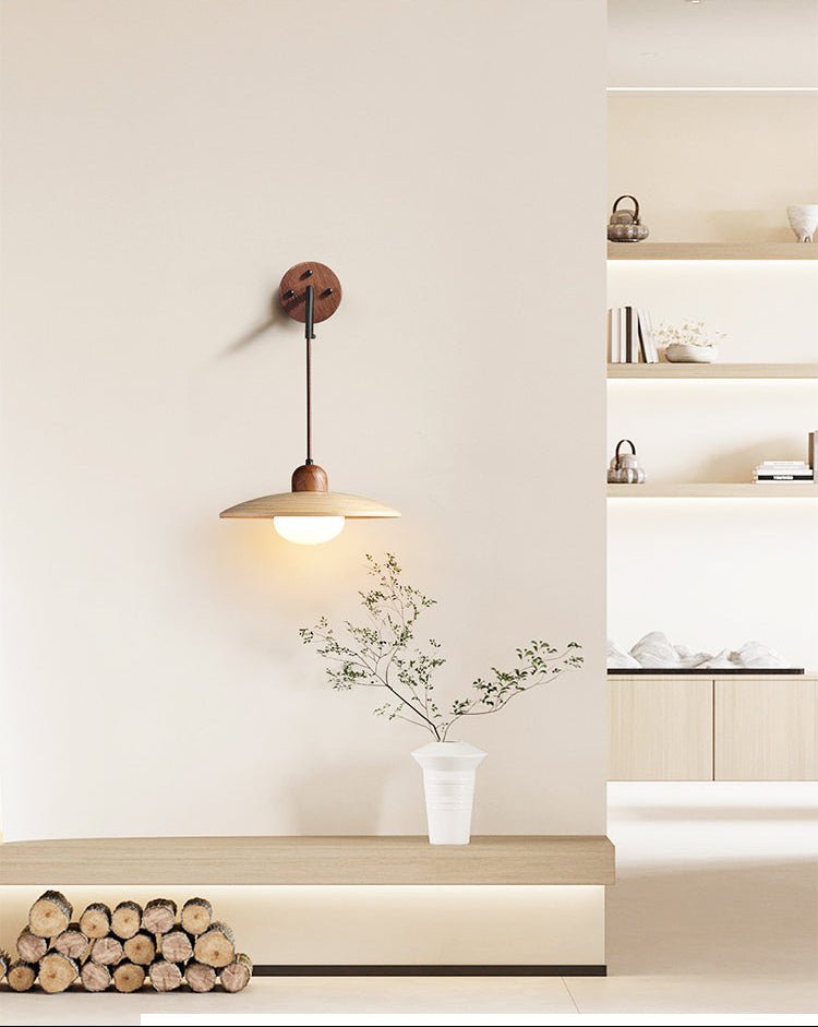 Sconce lit above a bench of logs and a vase of branches before open shelves