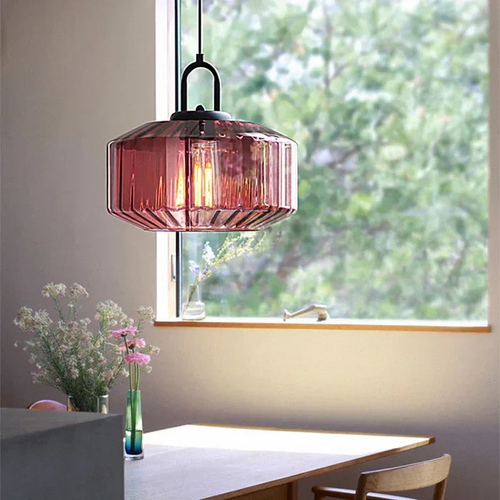 Purple ribbed drum shade hanging by a window above a wooden dining table
