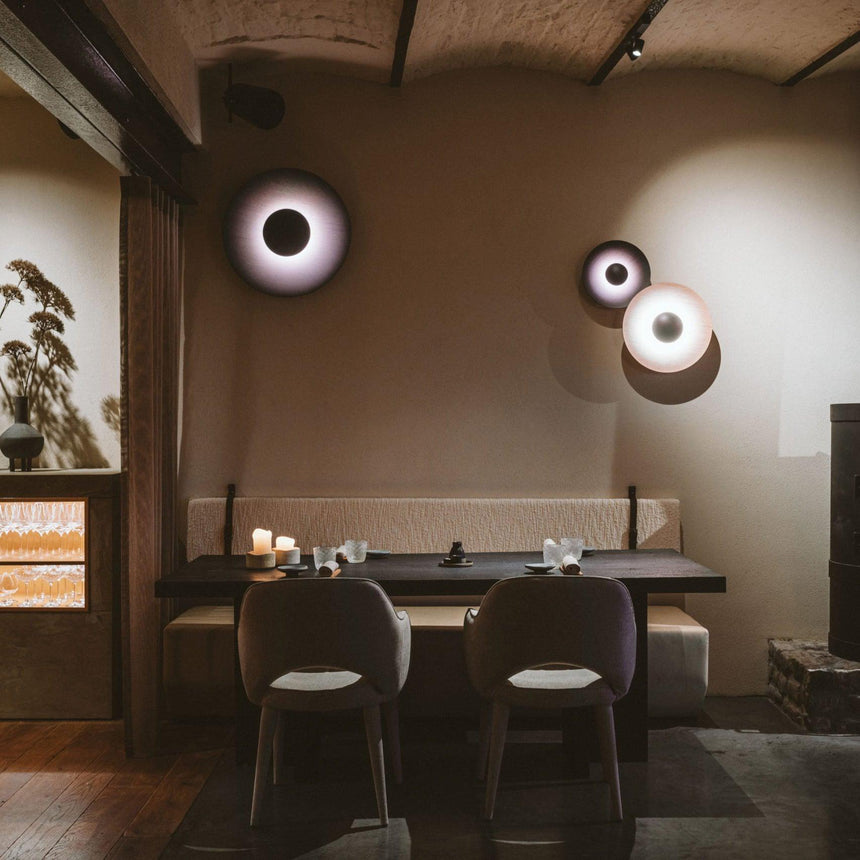 Disc lights glowing above a long banquette and dining chairs