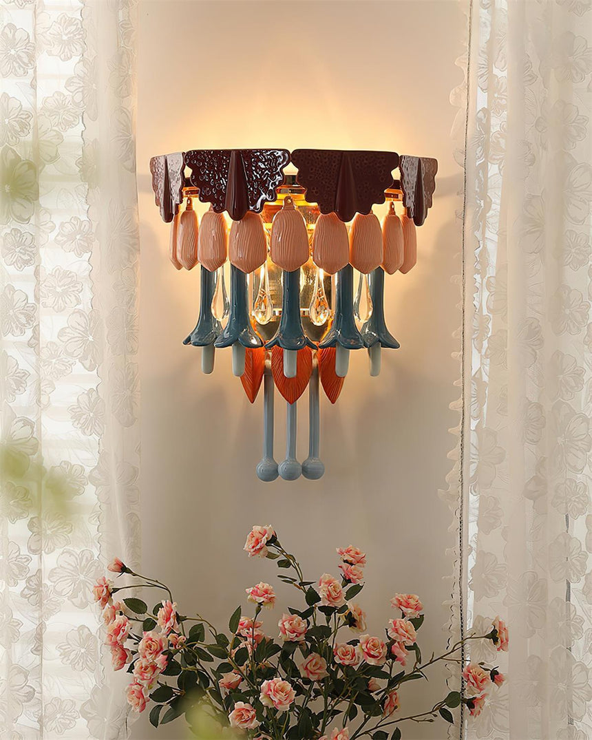 The sconce lit between sheer curtains above a bunch of pink roses