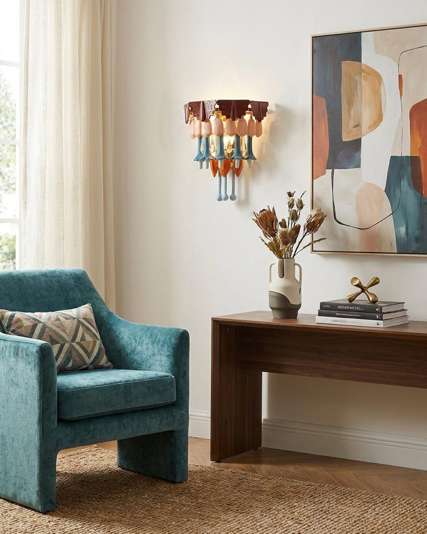 The colorful sconce above a wood desk beside a teal armchair and an abstract canvas