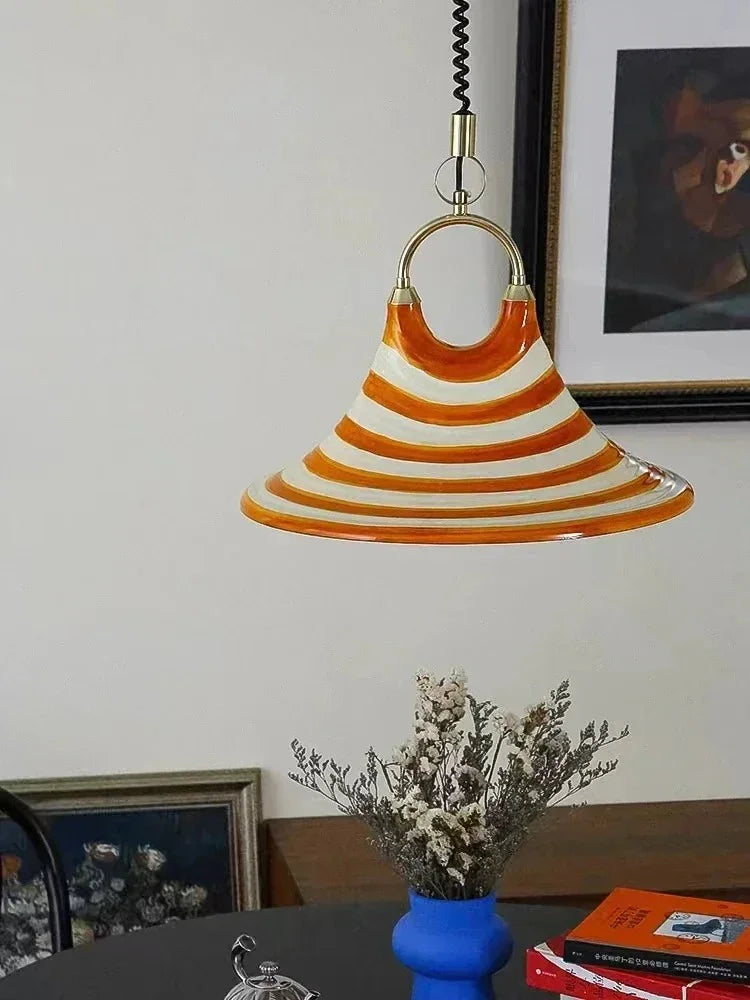 The striped cone lit above a shelf with a vase and dried flowers