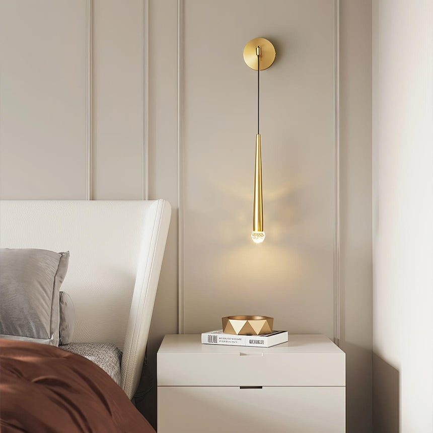 The brass cone lit above a white nightstand beside a bed