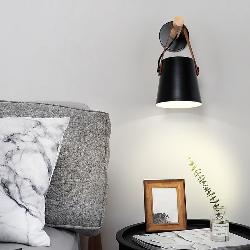 Sconce lit above a side table with a frame beside a gray armchair