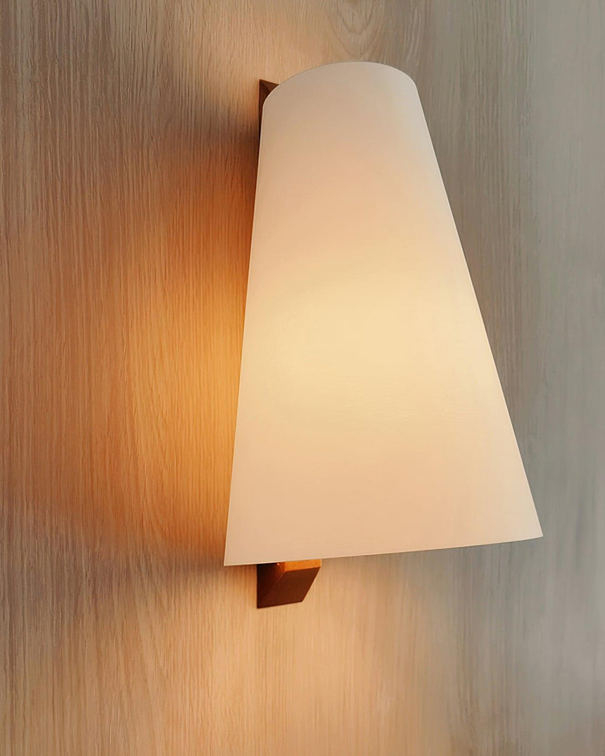 The cone shade lit against a wood wall, the folded bracket holding it out