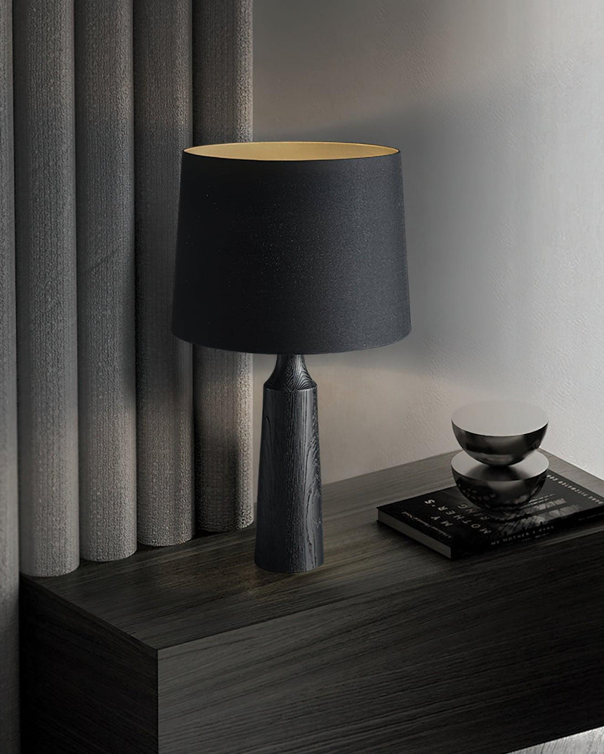 Console table lamp in black on a dark console beside a curtain