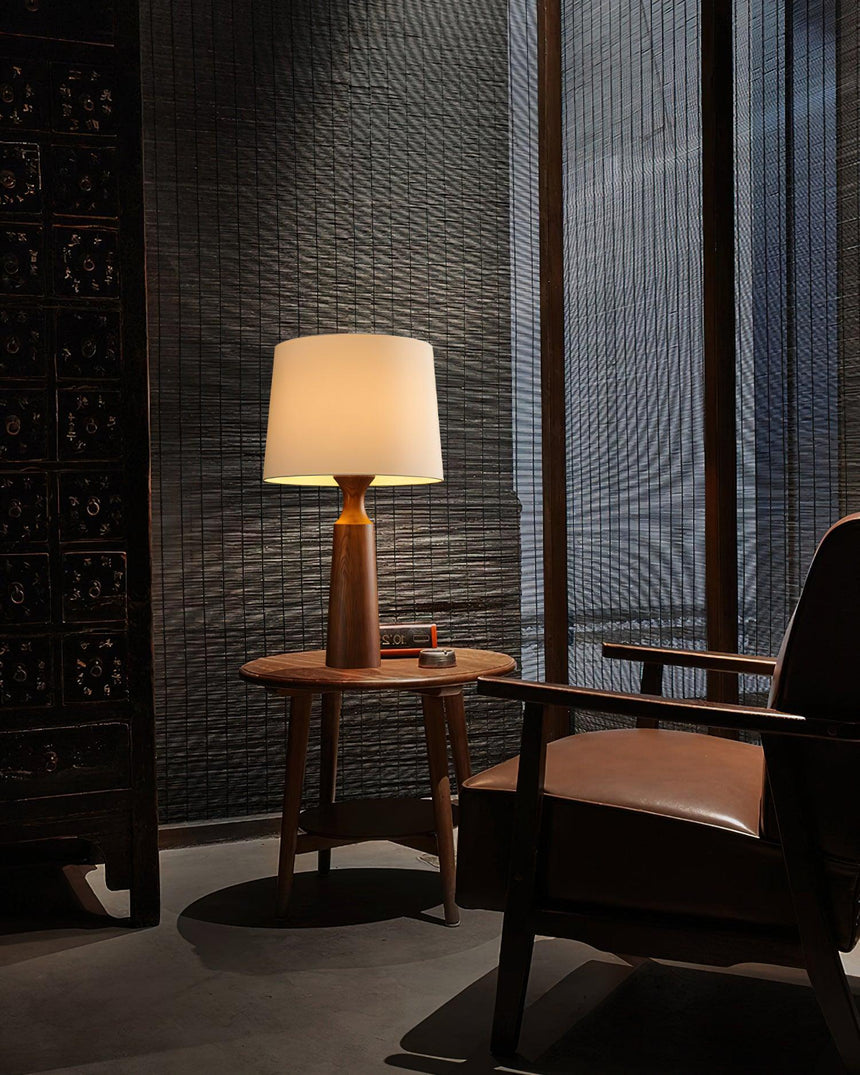 Console table lamp lit in a dark corner beside a leather chair