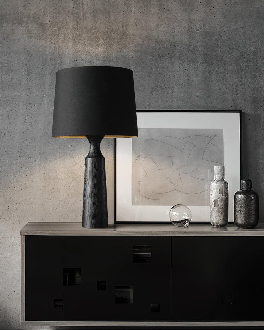Console table lamp in black on a sideboard beside framed prints