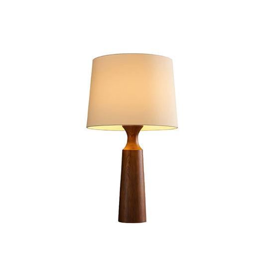 Console table lamp in walnut lit against a plain pale ground