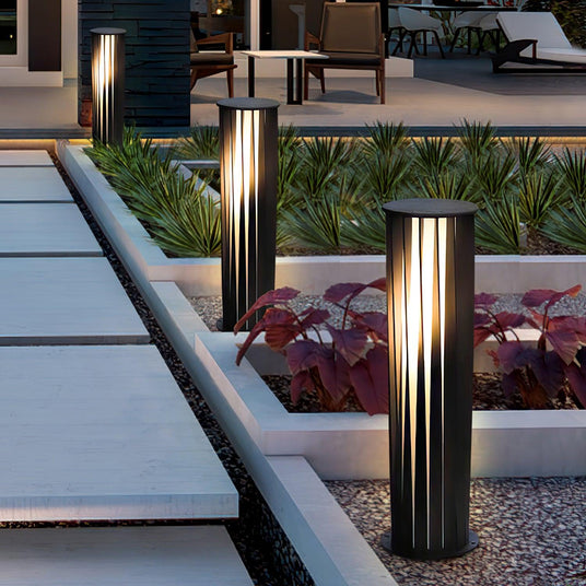Two lit at the edge of a raised planter beside a paved terrace walk