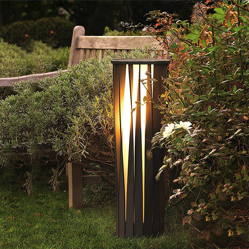 One lit in front of a stone bench with dense planting either side