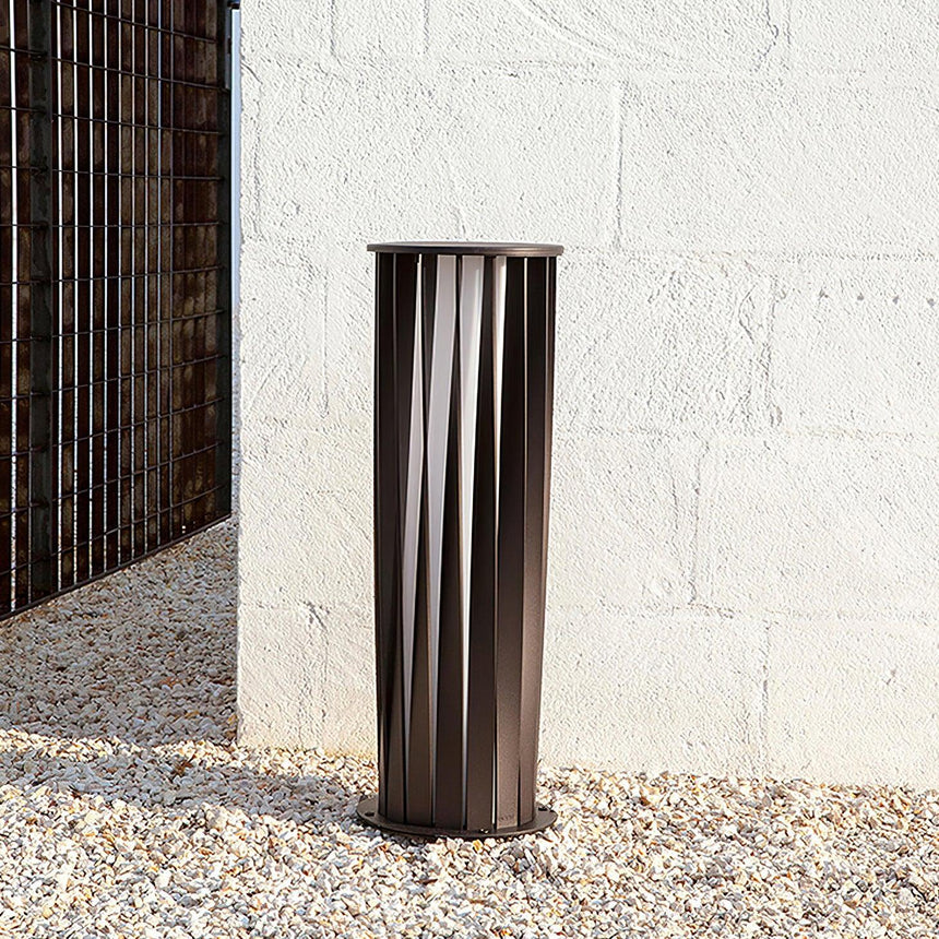 One lit against a white rendered wall standing on pale gravel