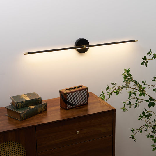 Black rod lit above a walnut cabinet with books, a radio and trailing foliage