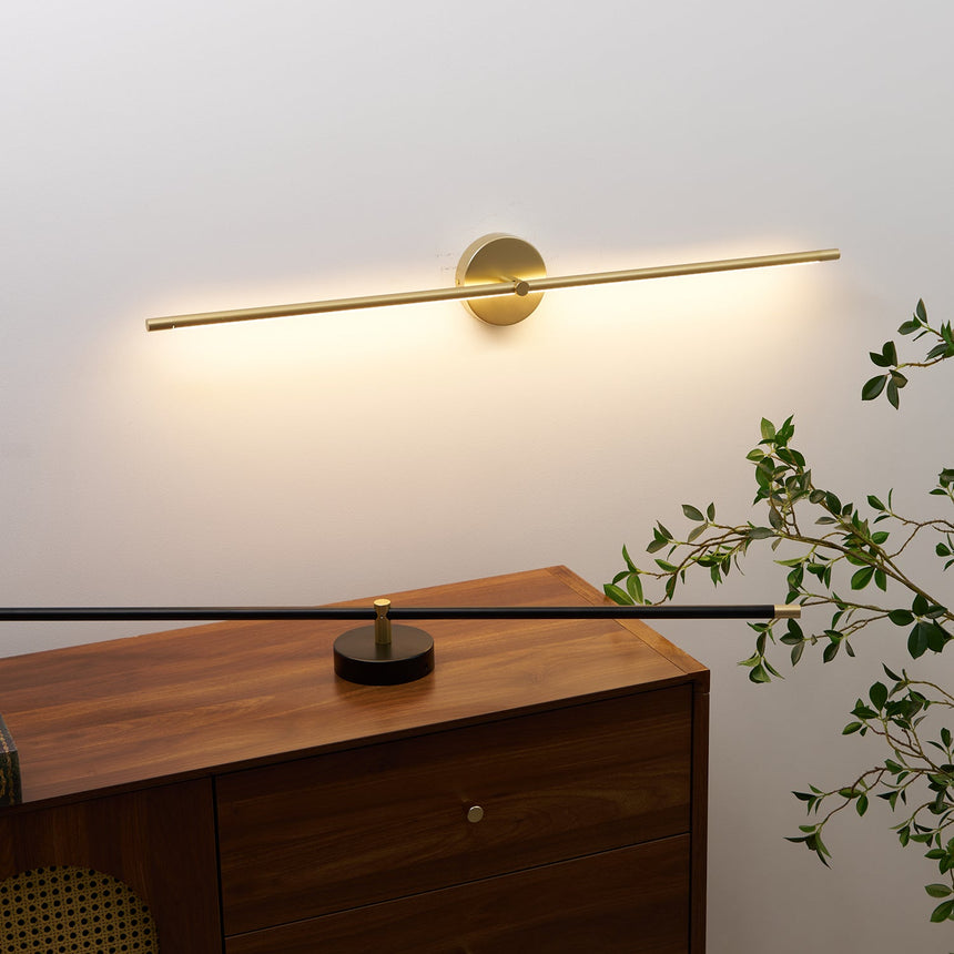 The long gold rod lit above a walnut cabinet, the wash reaching the shelf below