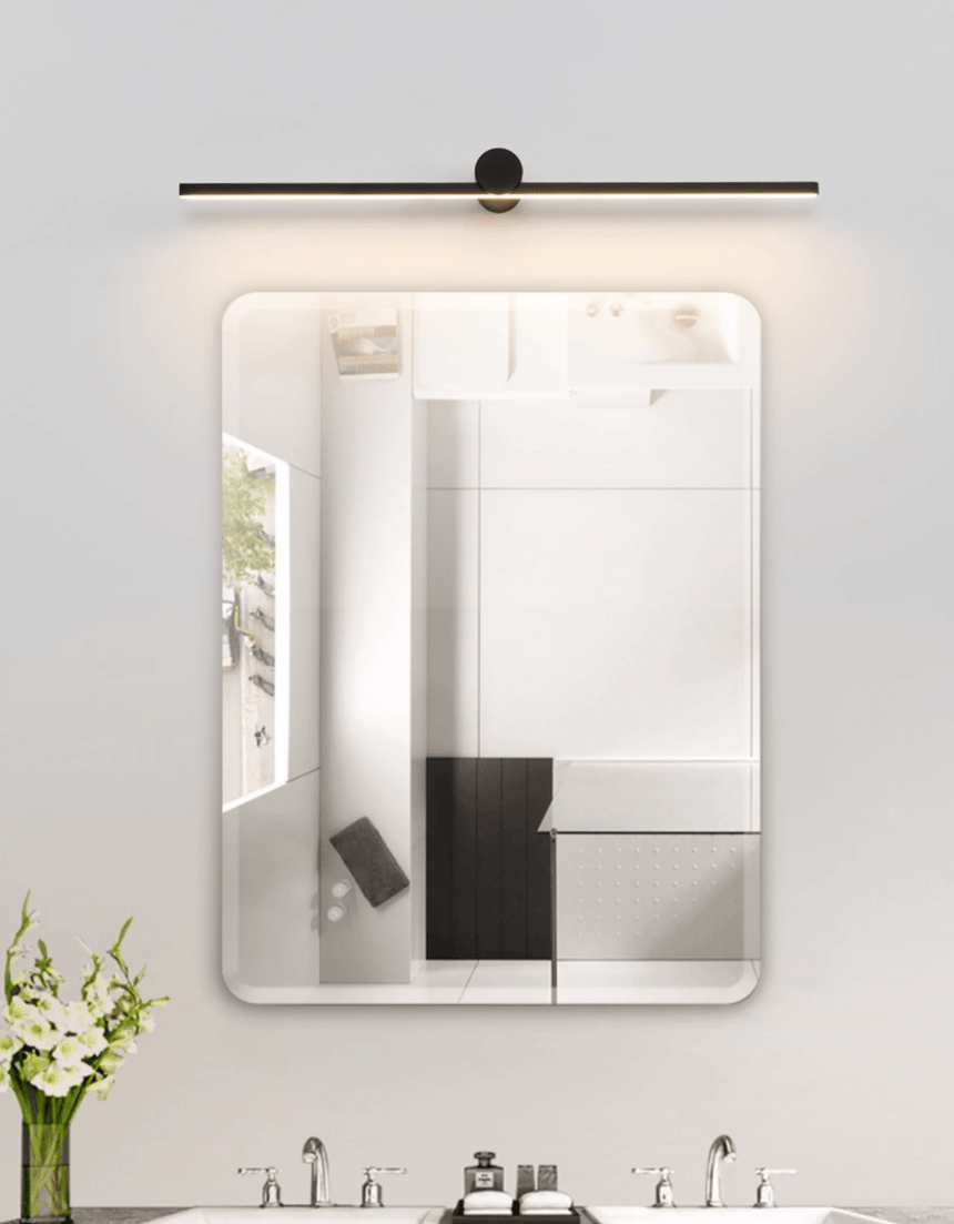 Black bar lit above a bathroom mirror over twin basins with white flowers