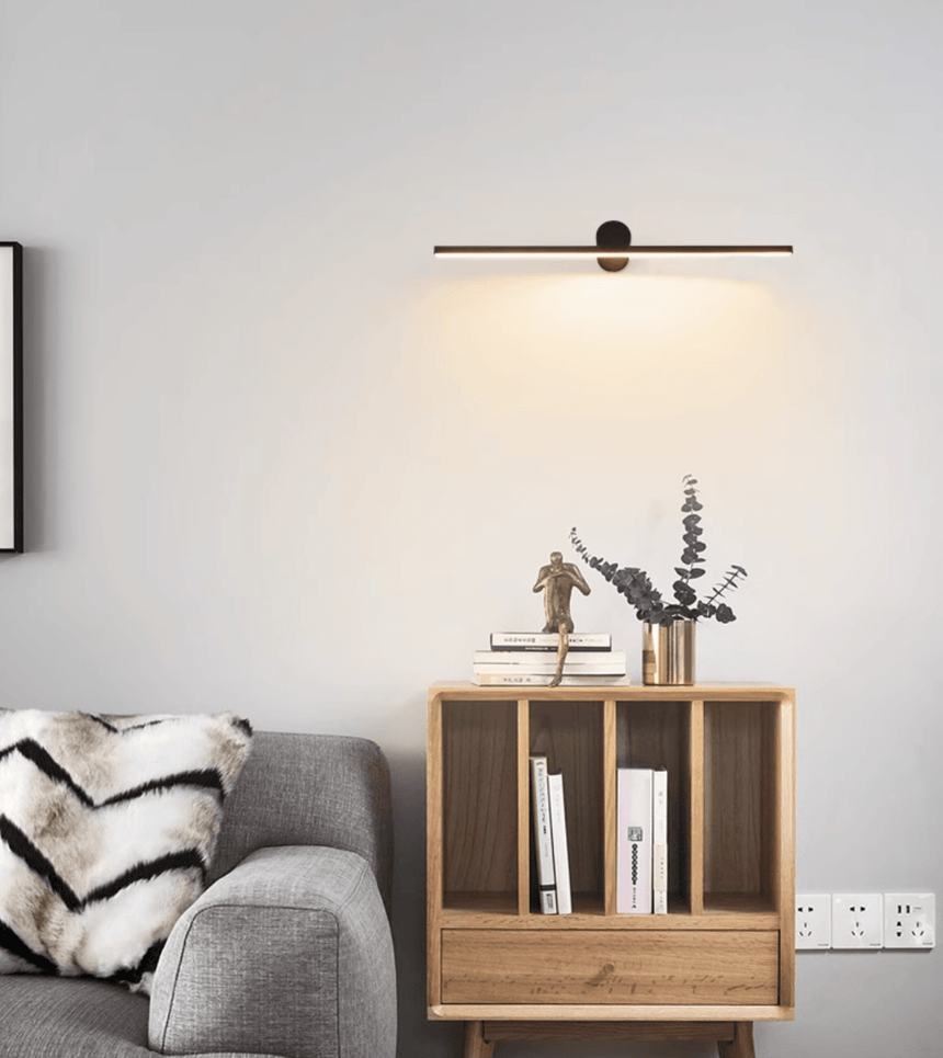 Black bar lit above a wood shelf unit of books beside a sofa with a throw