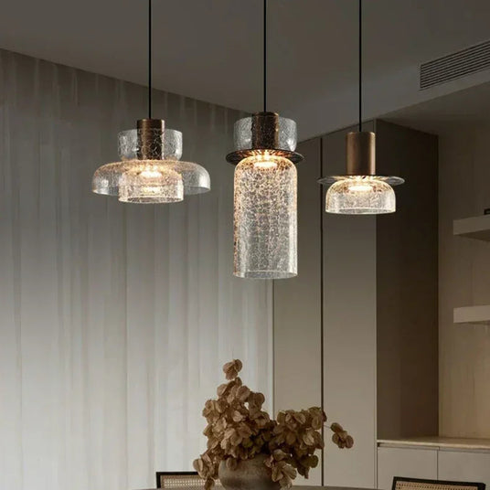Three crackle shades lit above a dining area with dried stems in a vase