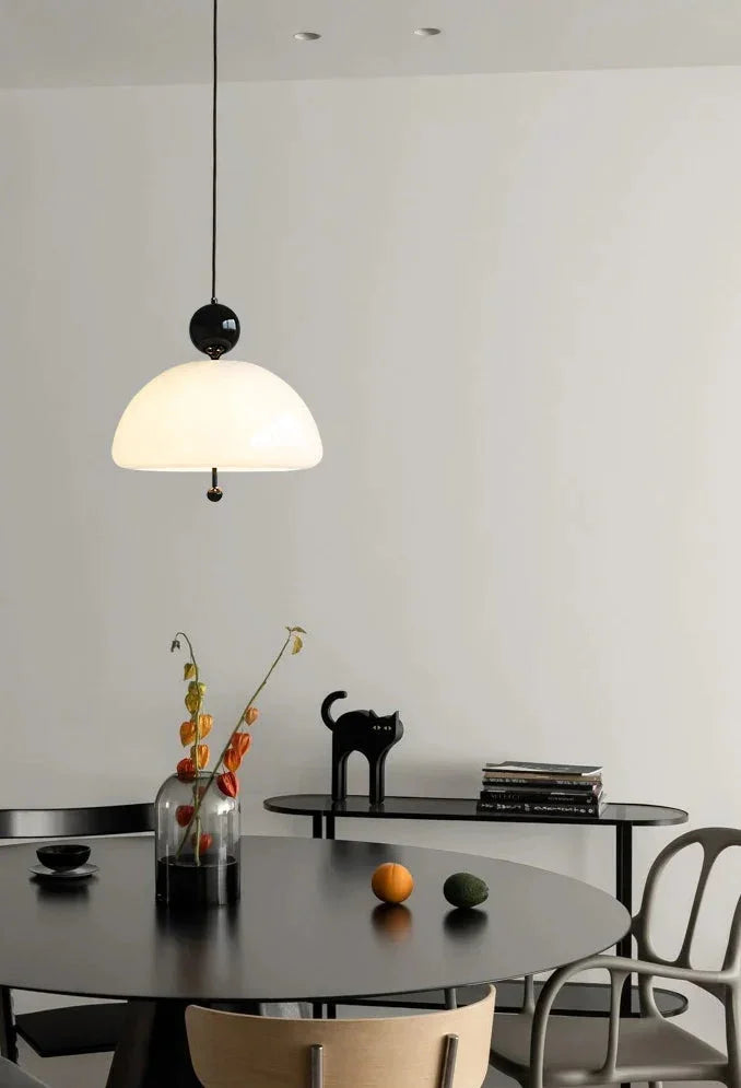 The cream dome lit above a dark dining table set with glasses and a vase