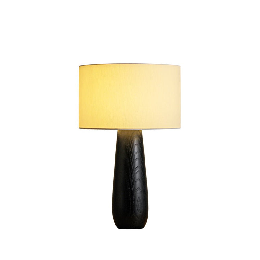 Cream table lamp on a black turned base, lit on a plain ground