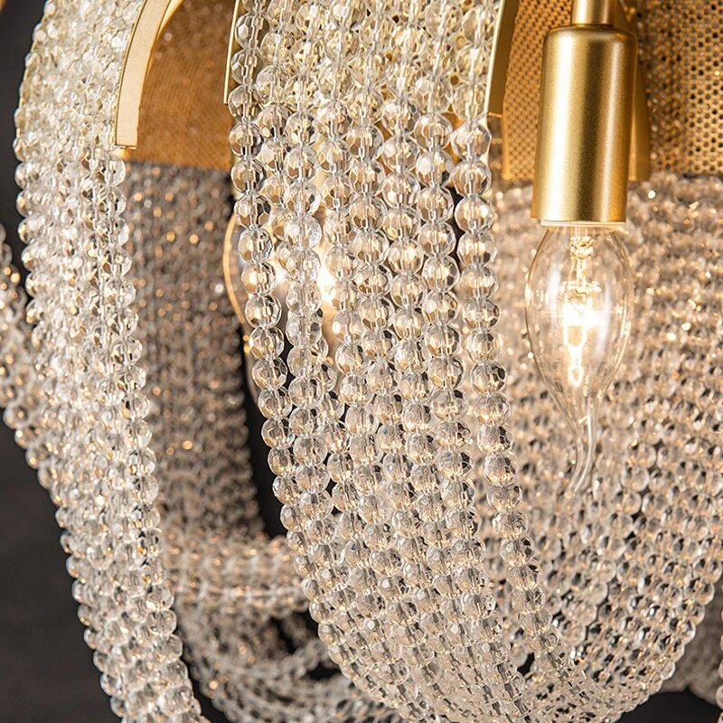 The crystal bead strands and one lit bulb seen close inside a gold arc