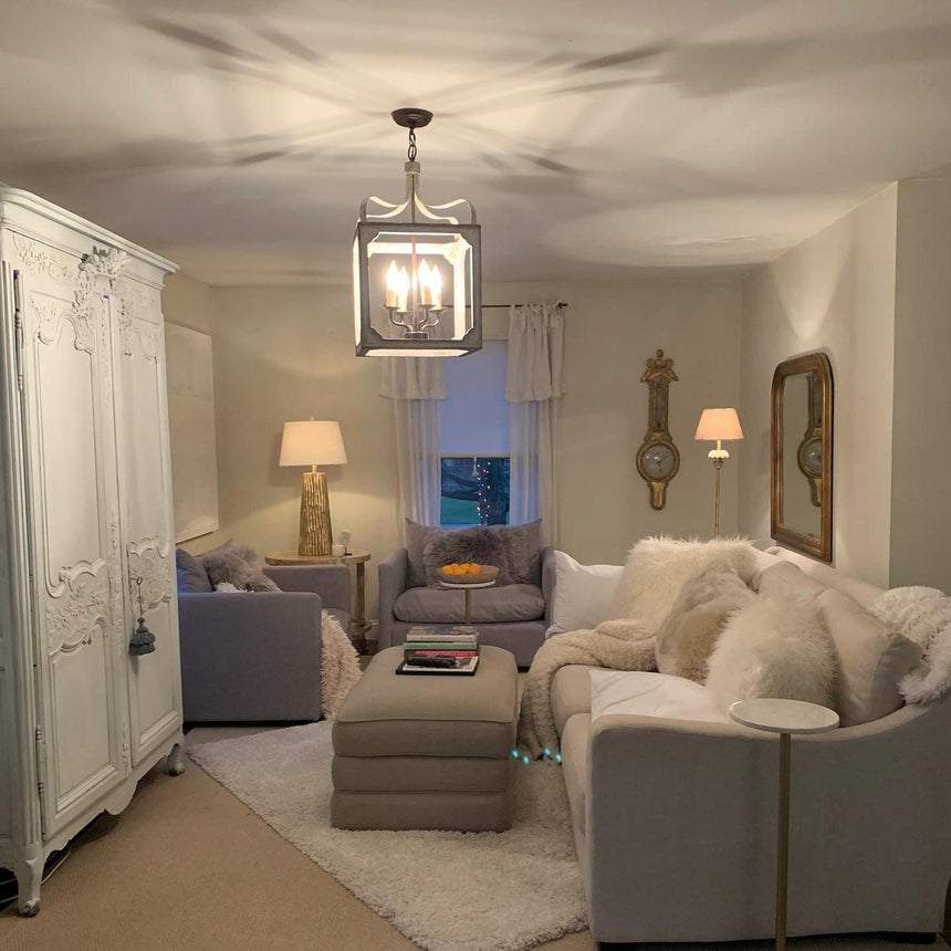 Lit in a room with a painted armoire, armchairs and a pale rug
