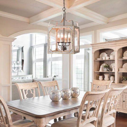 Lit above a pale dining table and chairs under a coffered ceiling with a dresser