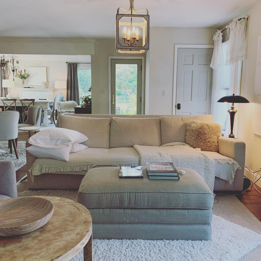 Hung in an open living room above a sofa, ottoman and round wood table