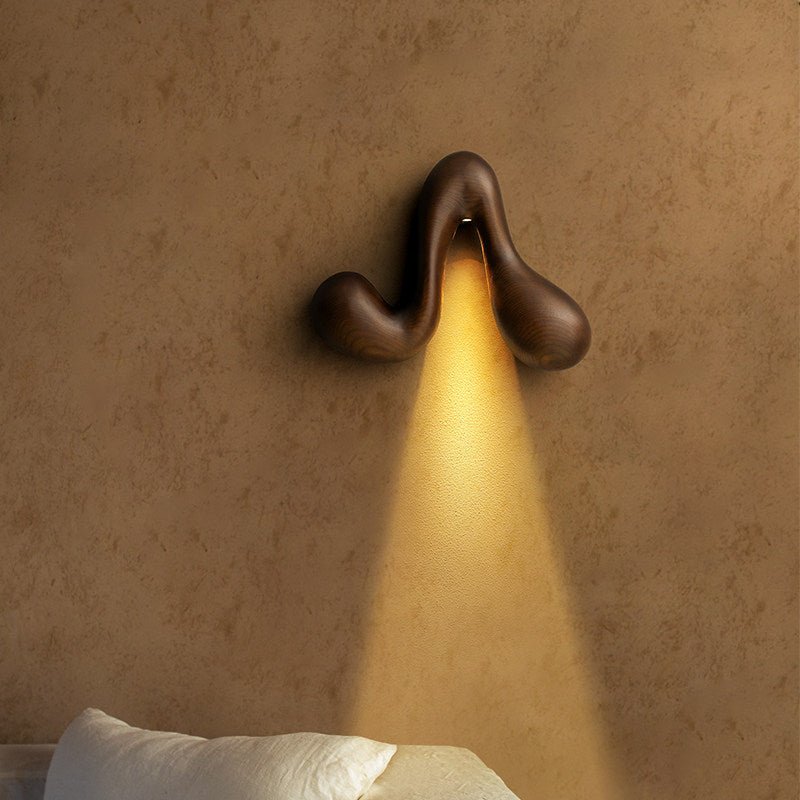 Sconce lit above a bed, a narrow cone of light falling onto the pillow