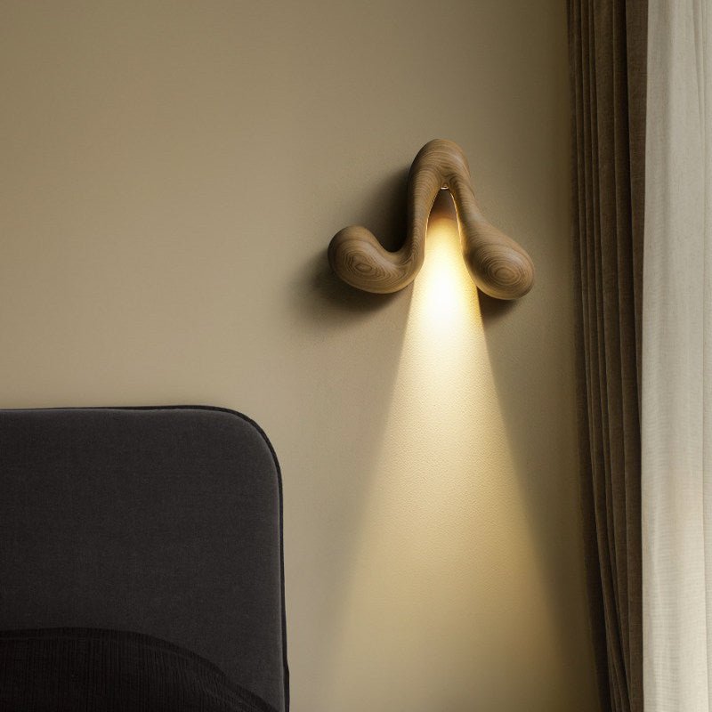 Sconce lit above a dark headboard with a curtain drawn at the side